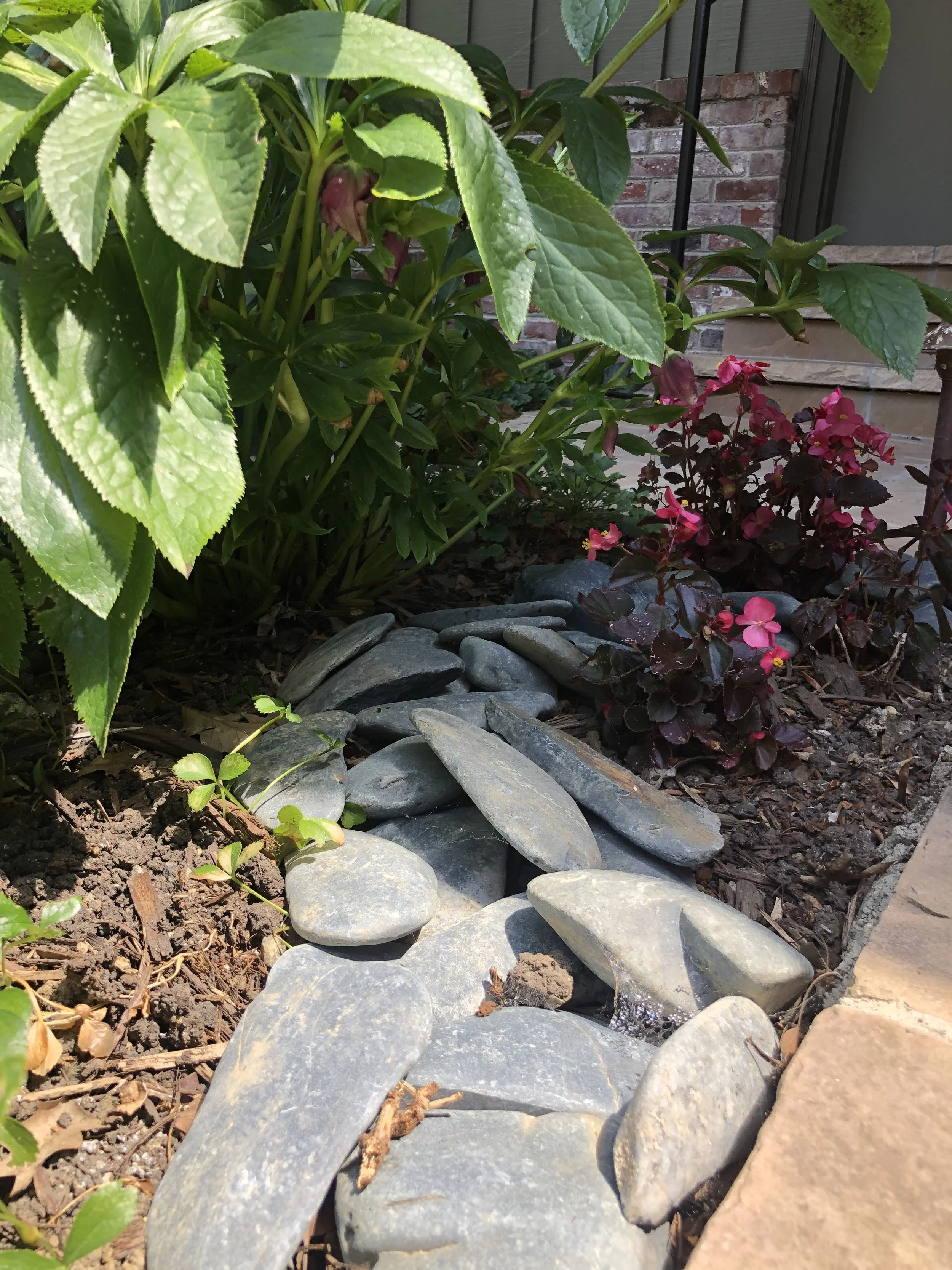 Planting bed with river rock edging and perennial flowers